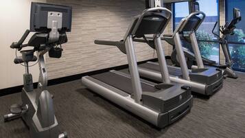 Ein Fitnessstudio mit Laufbändern, einem Ergometer und einem Rudergerät.