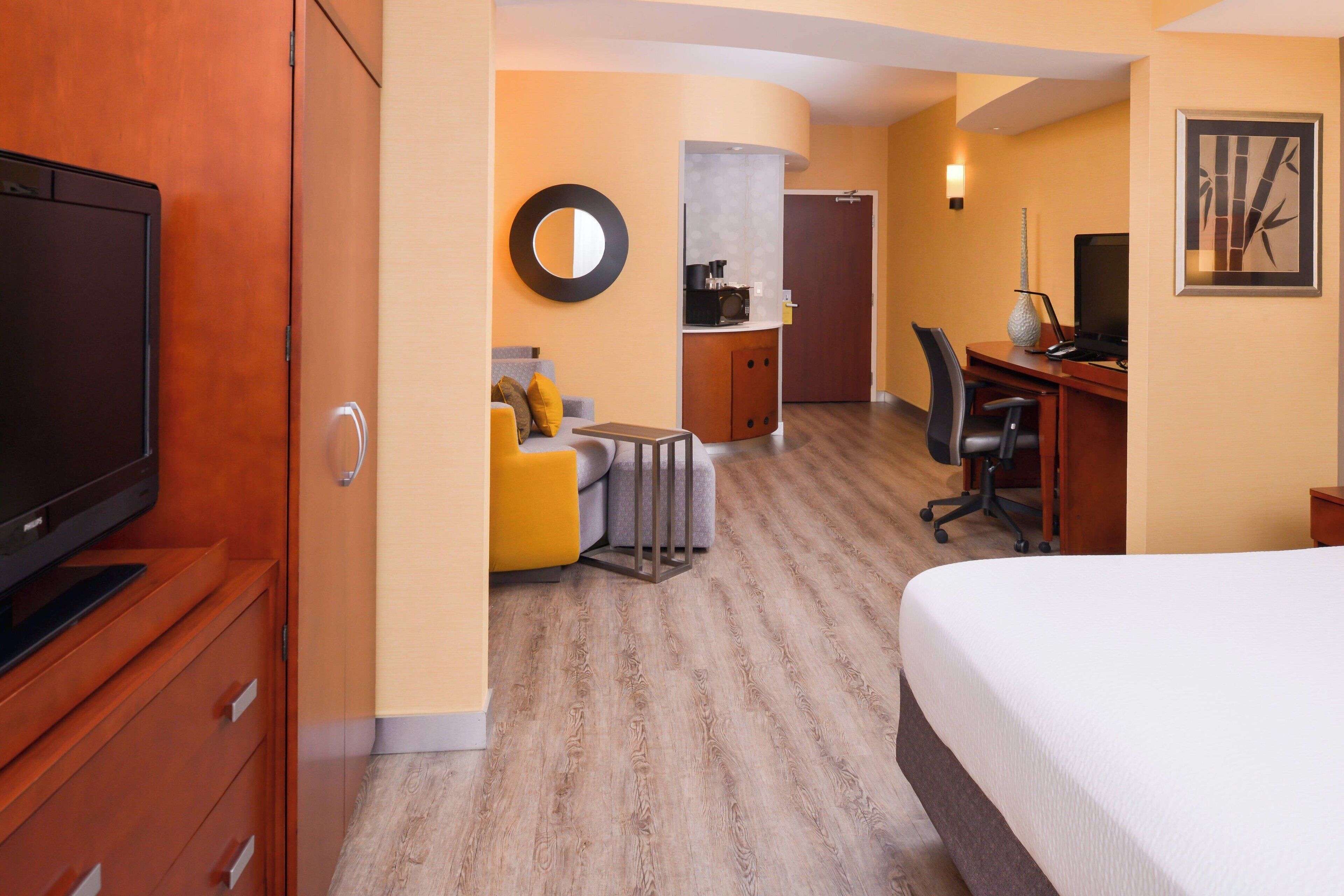 A hotel room with a bed, a desk, a chair, a television, a wardrobe, and a bathroom.