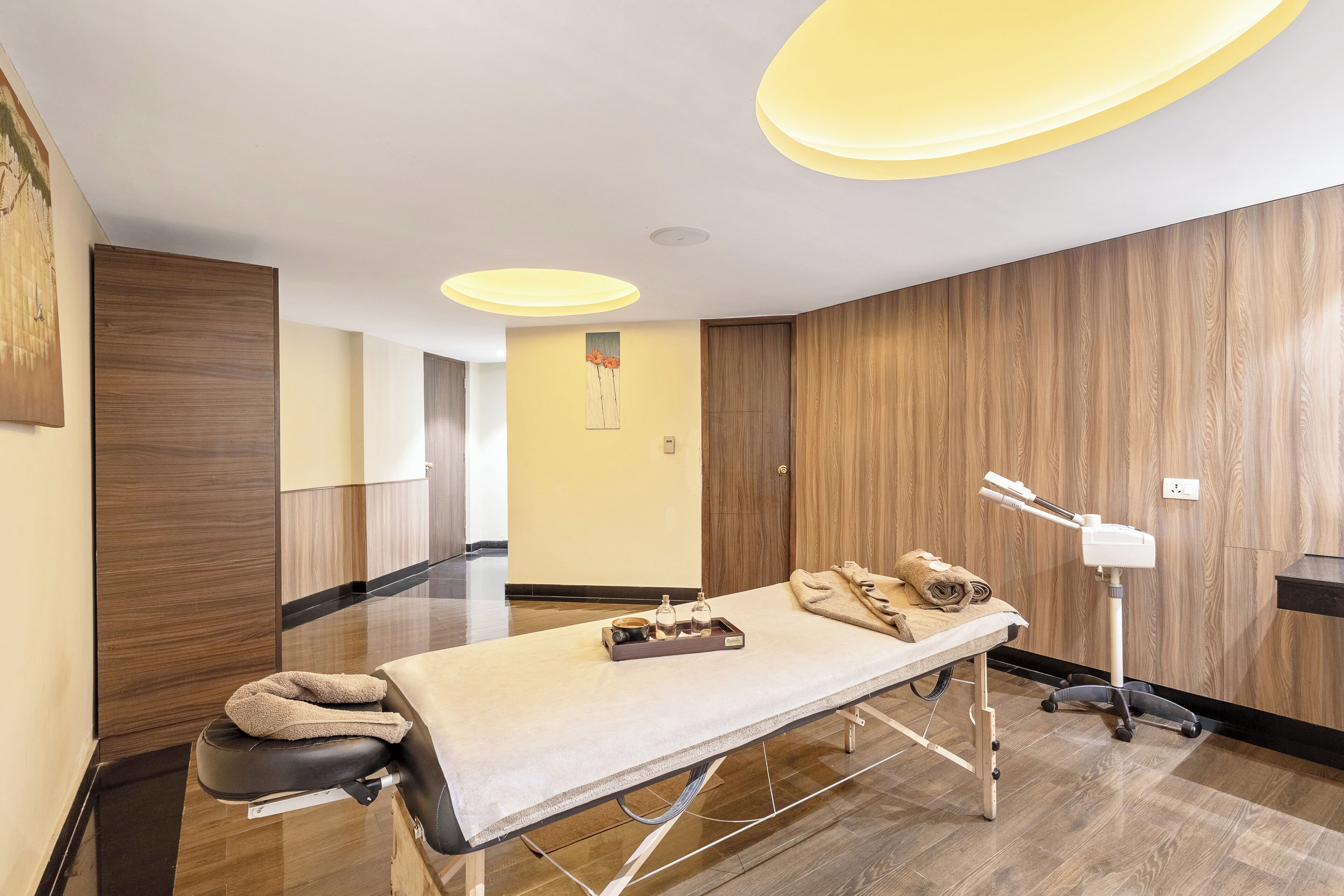 Una habitación moderna con una mesa de masajes, paneles de madera y un lámpara en el techo.