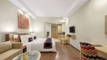Una habitación de hotel con una cama, un sofá, un escritorio, un televisor y una silla.