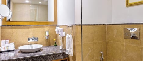 Un baño moderno con tocador de mármol, un espejo grande, inodoro y zona de ducha.