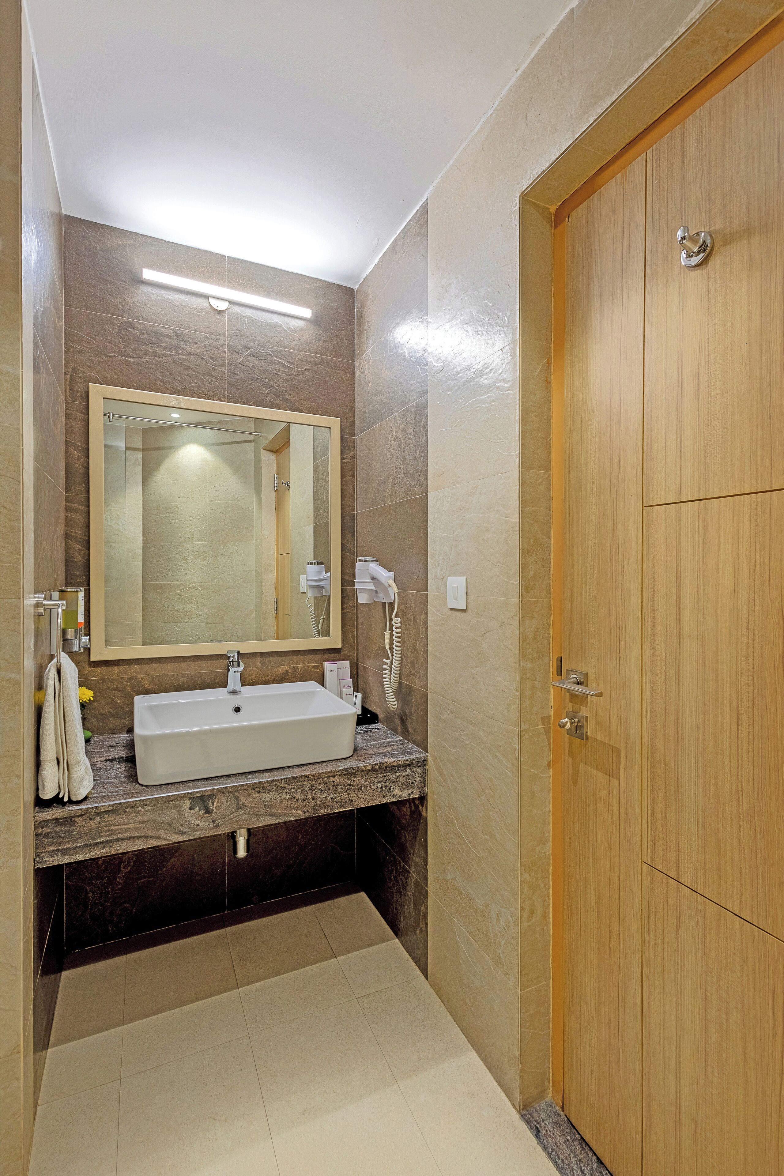 A bathroom with a sink, mirror, and wooden door.