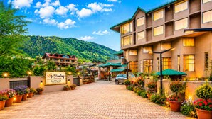 Ein Hotel Eingang mit befestigter Auffahrt, Blumentöpfen und einem Schild für Sterling Manali.