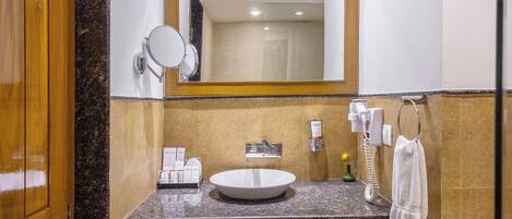 A bathroom with a wooden door, a sink, a mirror, and a towel rack.