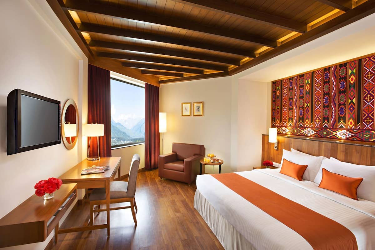 Ein Hotelzimmer mit Bett, Schreibtisch, Stuhl, Fernseher und Bergblick.
