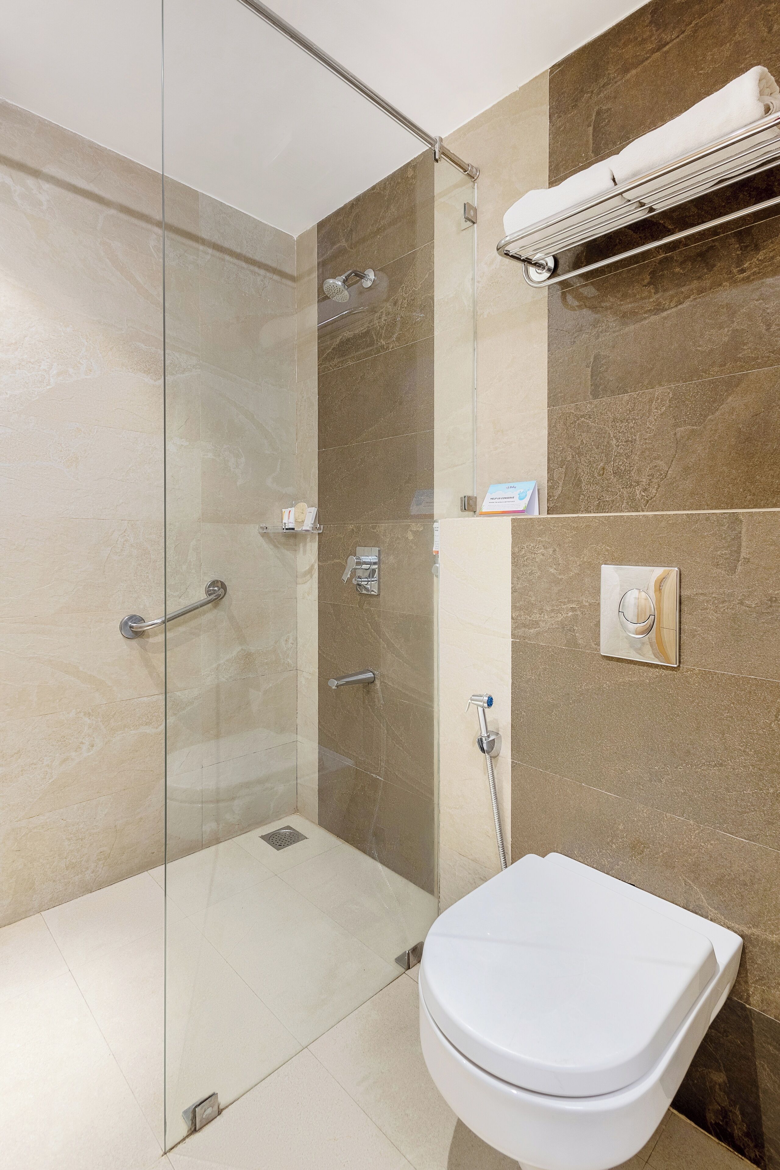 Ein modernes Badezimmer mit einer gläsernen Duschkabine, einer weißen Toilette und einem Handtuchhalter.
