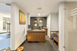 A reception desk with a wooden finish, a painting above it, and a small plate with food and a candle on the floor.