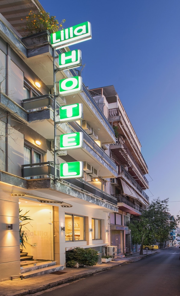 Un hôtel reconnaissable à son grand panneau néon vert sur lequel on peut lire « Lilia Hotel ».