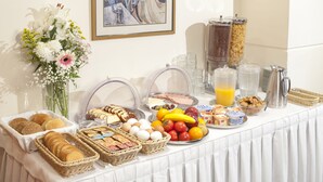 Un bufé de desayuno con diversos alimentos, como pan, huevos, frutas y bebidas.