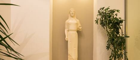 A statue in a recessed alcove, a potted plant, and a marble bench.