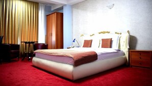 A hotel room with a large bed, a desk, a chair, a wardrobe, and a nightstand. - Aristocrat Hotel (Skopje)