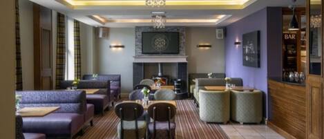 A modern lounge area with seating, a fireplace, and a bar.