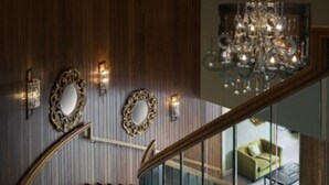 Un magnifique escalier en bois, orné de boiseries et surmonté d’un lustre.