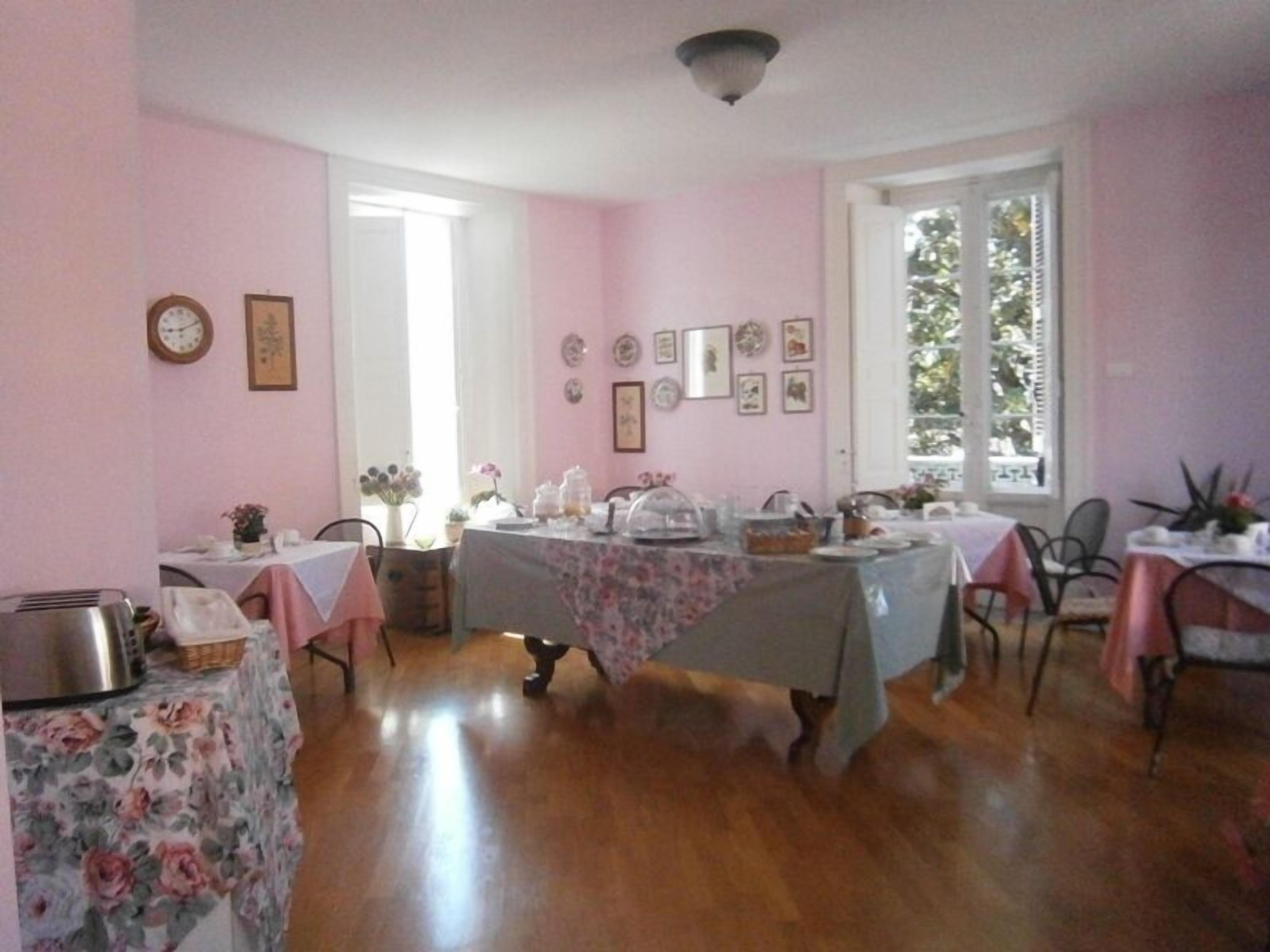 A dining area with pink walls, wooden flooring, and tables set for a meal.