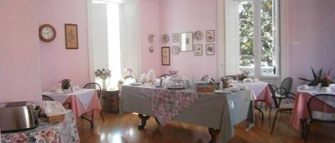 A dining area with pink walls, wooden flooring, and tables set for a meal.