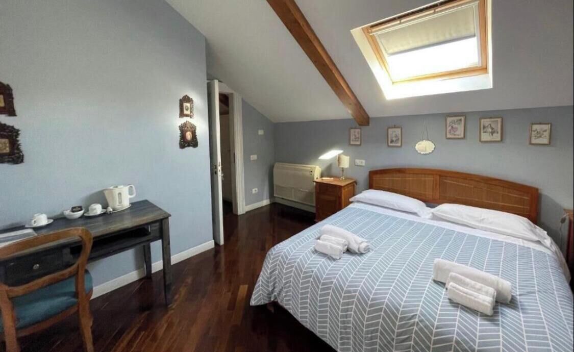 A bedroom with a bed, a desk, a chair, a window, and a ceiling fan.
