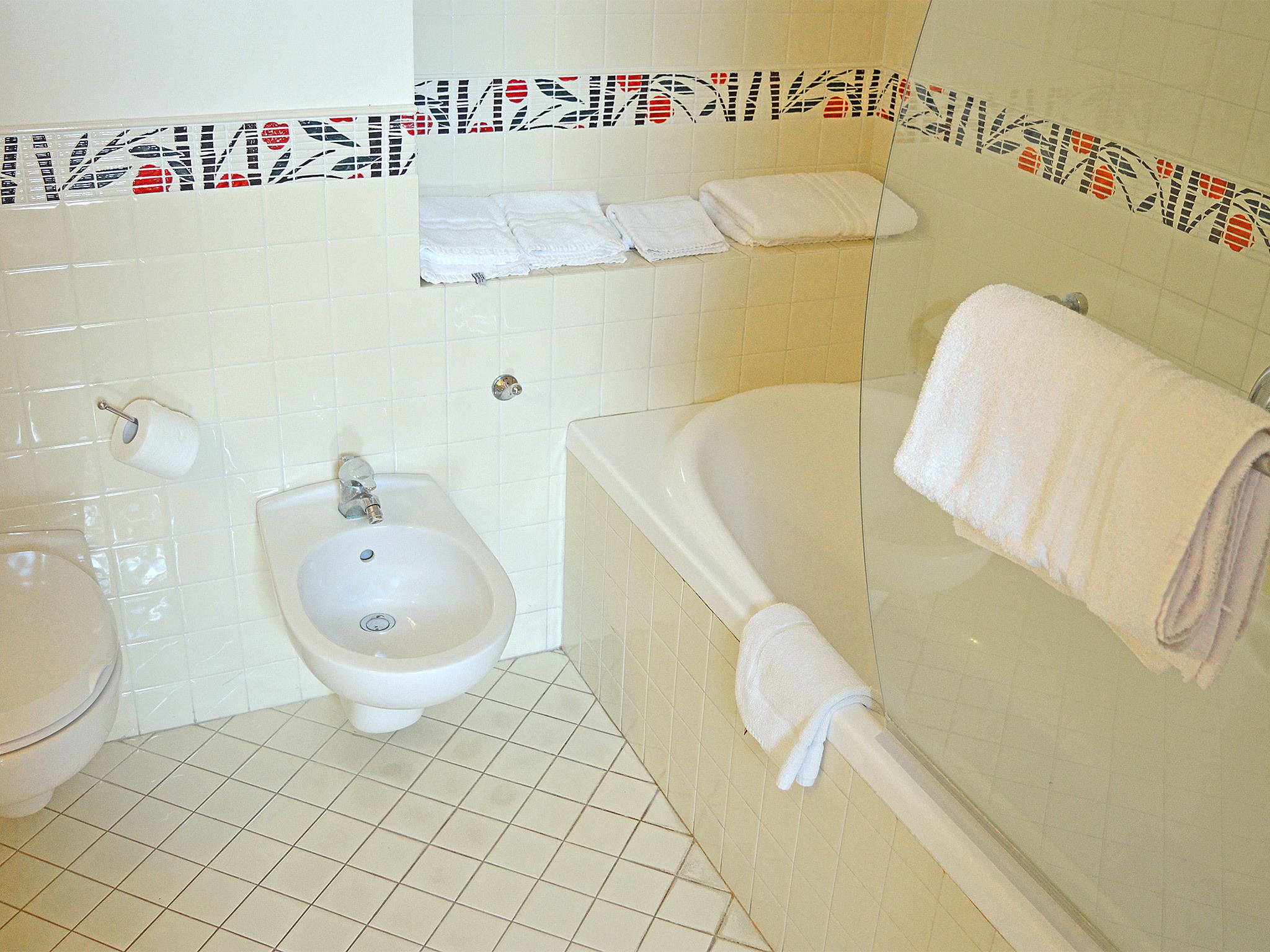 A bathroom with a bidet, a sink, and a bathtub.