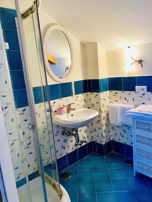 Een badkamer met een douche, wastafel en spiegel.