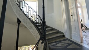 A spiral staircase with ornate black railings and a white wall.