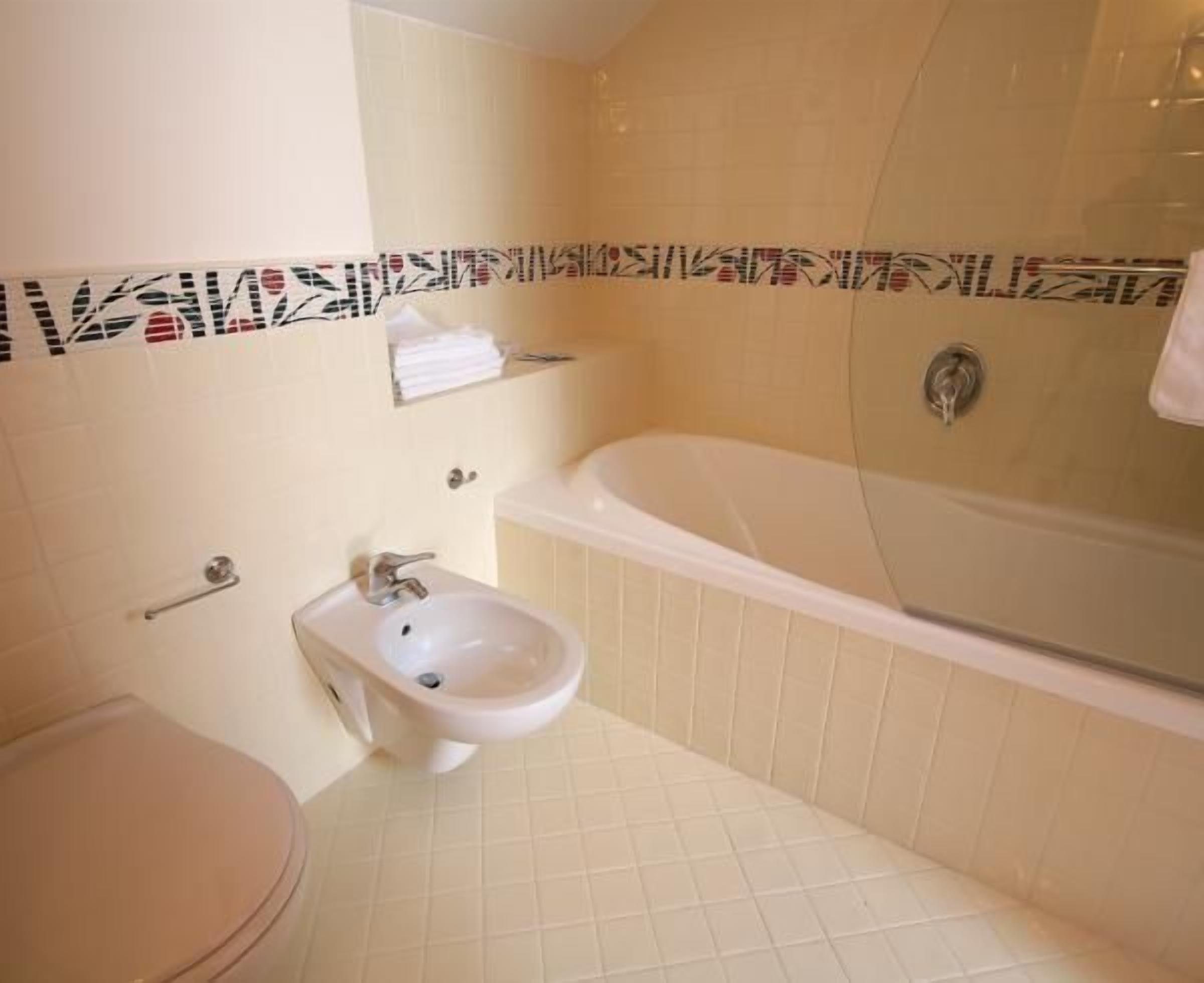 Een badkamer met een bad, een hygiëneschuimer en een toilet.