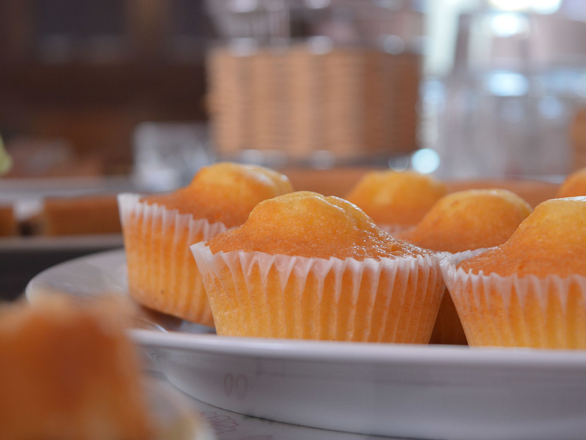 A plate of round, golden-brown pastries in white paper cups.