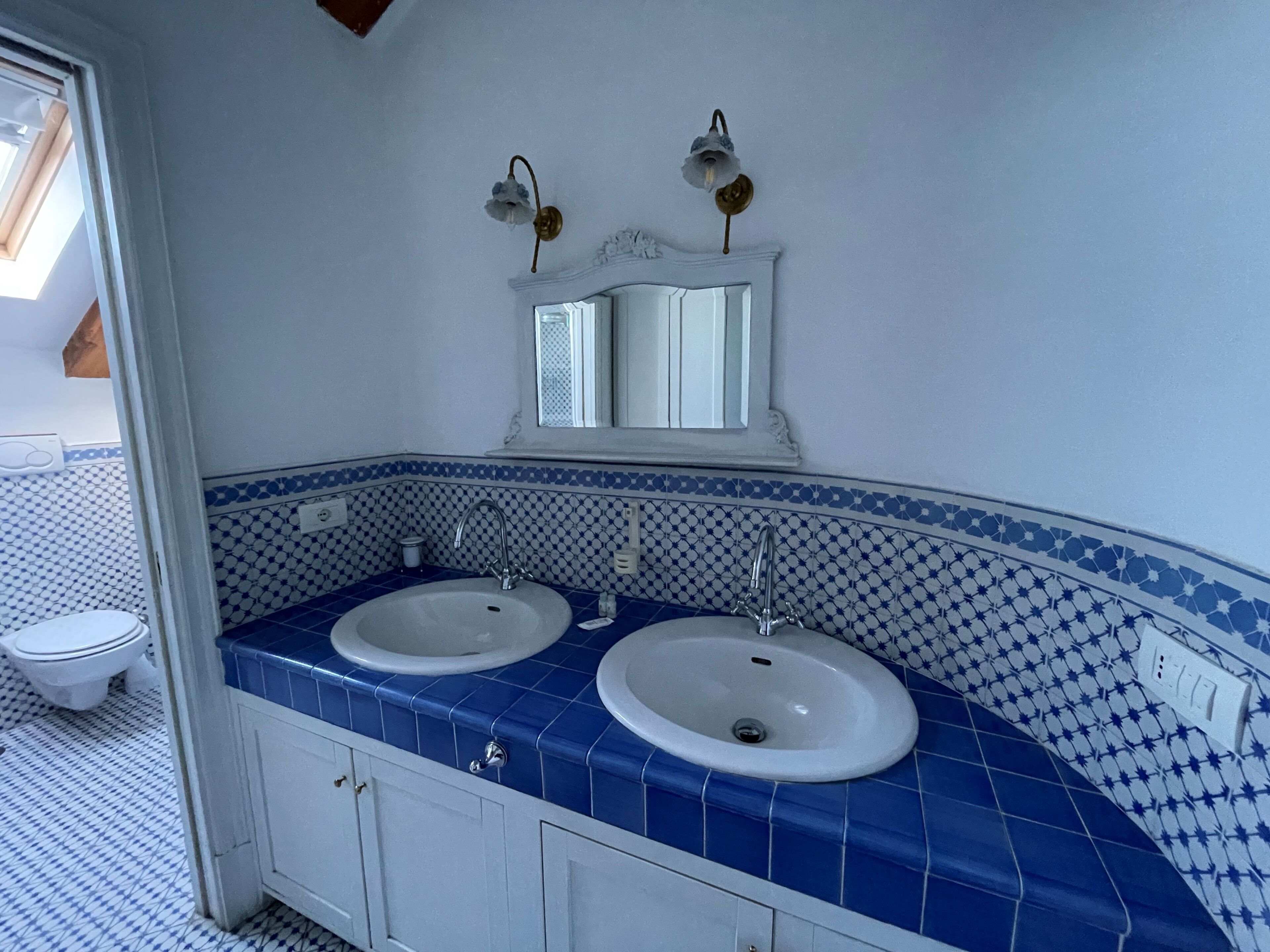 A bathroom with two sinks, a mirror, and a toilet.