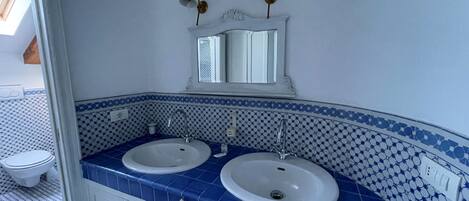 A bathroom with two sinks, a mirror, and a toilet.
