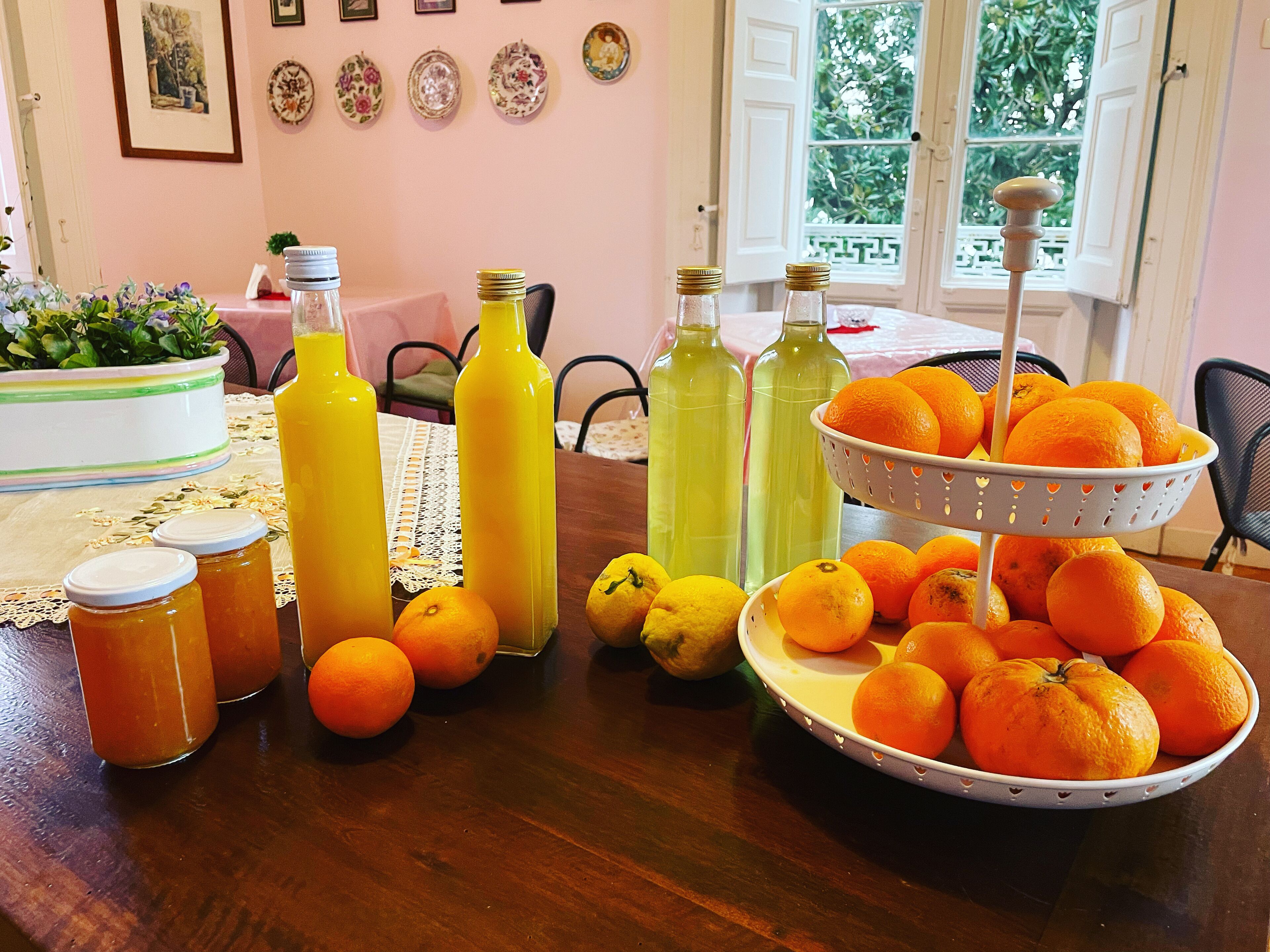 Ein Esstisch mit verschiedenen Früchten, Flaschen und einem Korb Orangen.