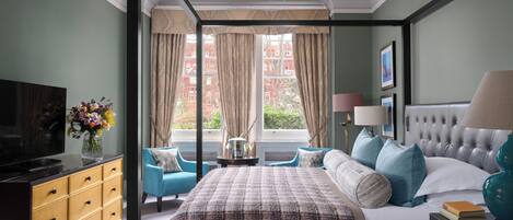 A bedroom with a bed, a TV, a dresser, and a window with curtains.