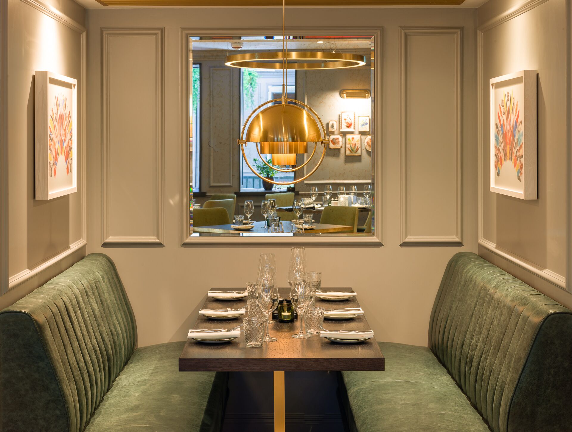 A dining area with a table set for four, a large window with a view of the interior, and a modern pendant light above the table.
