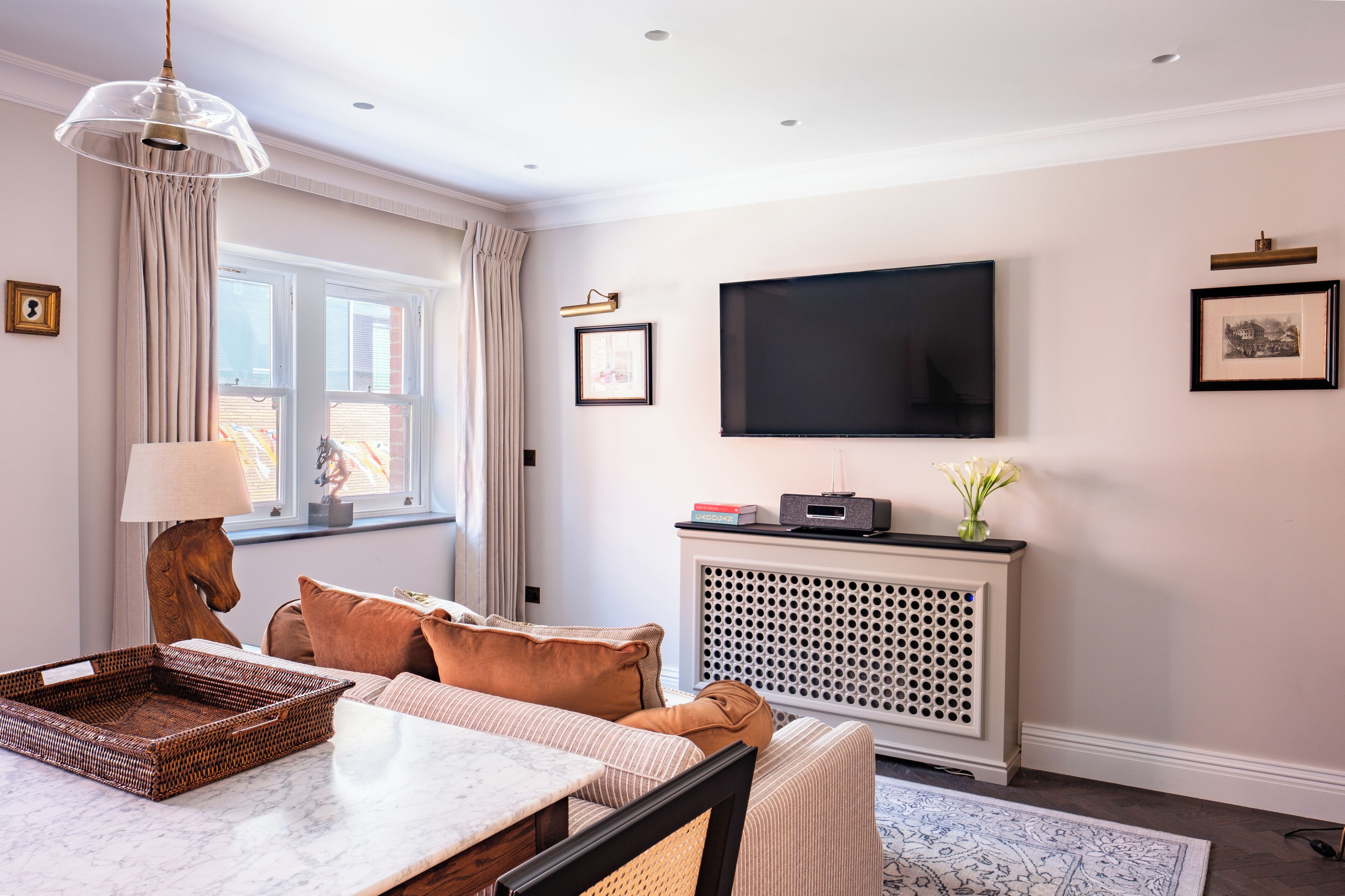 A modern living room with a marble table, comfortable seating, a mounted TV, and a decorative console.