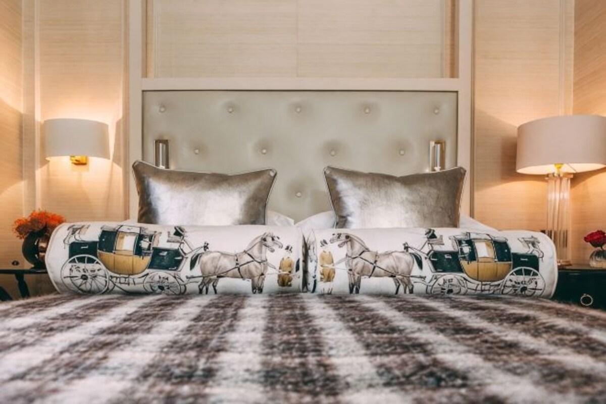 A bed with a tufted headboard, two bedside lamps, and a patterned throw blanket.