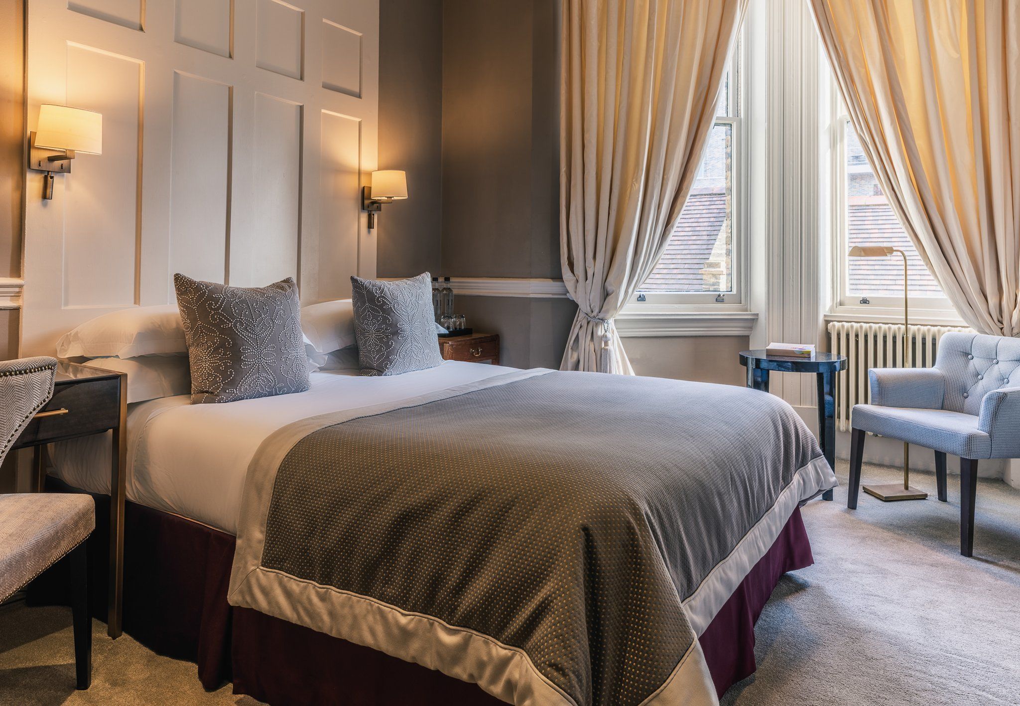 Ein Hotelzimmer mit einem großen Bett, einem Sessel, einem Nachttisch und einer Lampe.