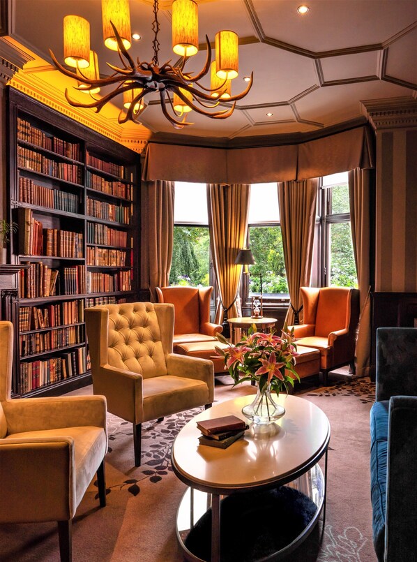 Une bibliothèque bien éclairée, dotée d’une grande bibliothèque, de sièges confortables et d’un lustre.