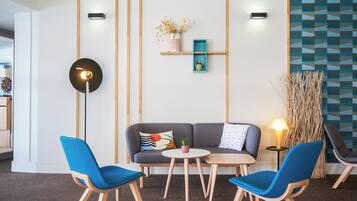 Una moderna zona relax con un divano, due poltrone blu, un tavolino e una lampada da terra.