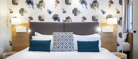 A hotel room with a large bed, two nightstands, and a wall with a leaf pattern.
