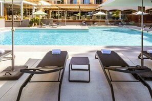 A poolside area with sun loungers, umbrellas, and a view of the pool.