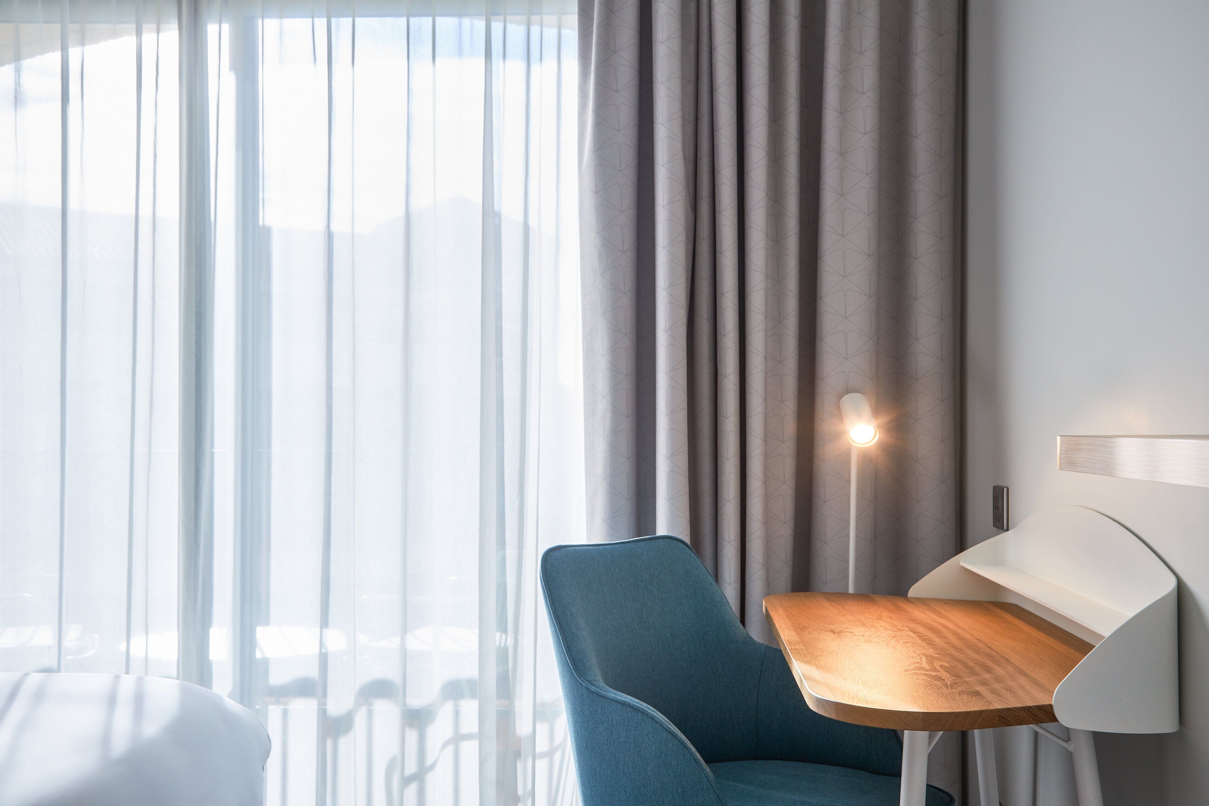 Una habitación moderna con una silla azul, una mesa de madera y una lámpara.