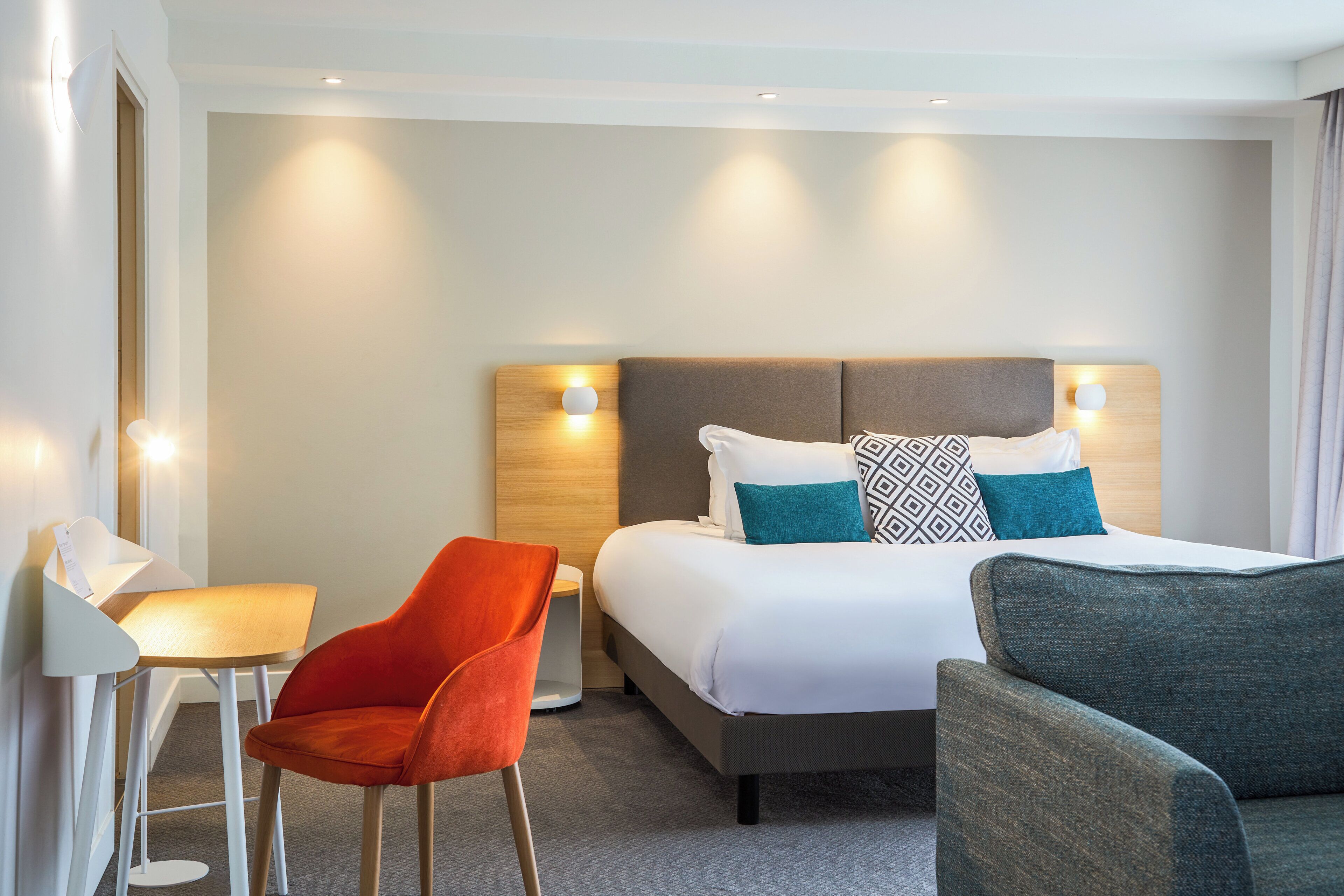 Ein Hotelzimmer mit einem Bett, zwei Stühlen, einem Schreibtisch und einem Nachttisch.
