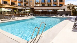 A swimming pool with sun loungers and umbrellas, surrounded by a building with balconies. - Holiday Inn Perpignan by IHG (Perpignan)