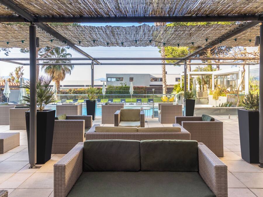 An outdoor seating area with wicker furniture and a pool in the background.