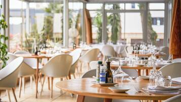 Een restaurant met ronde tafels, stoelen en servies.