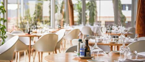 A restaurant with round tables, chairs, and dining ware.