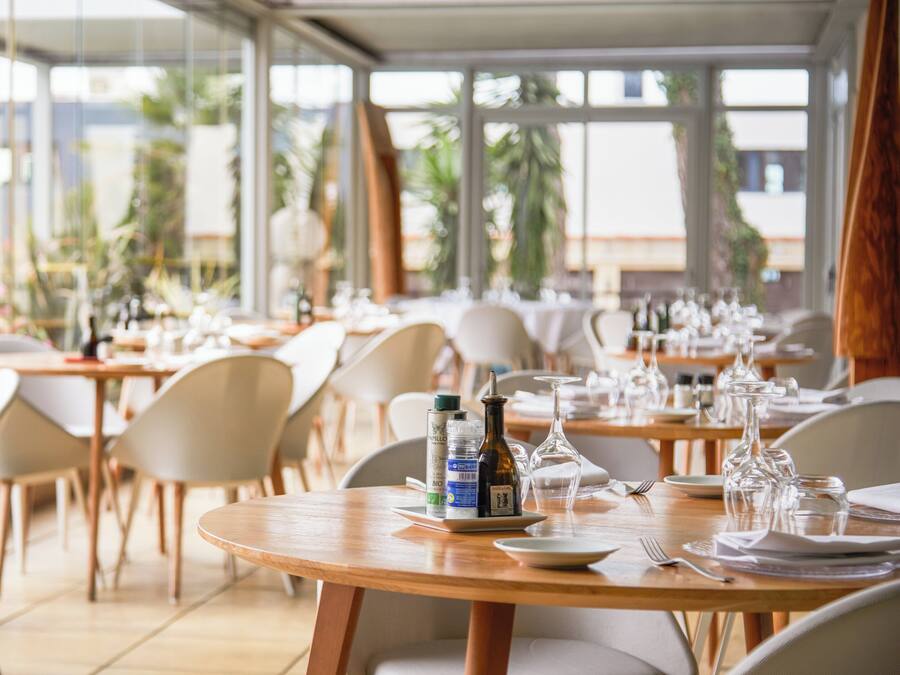A restaurant with round tables, chairs, and dining ware.
