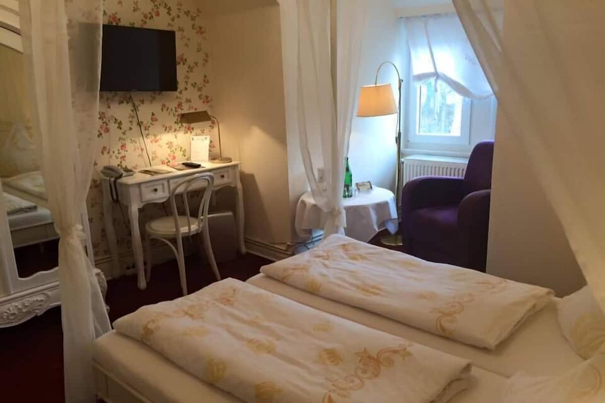 Een slaapkamer met twee bedden, een bureau, een stoel en een televisie.