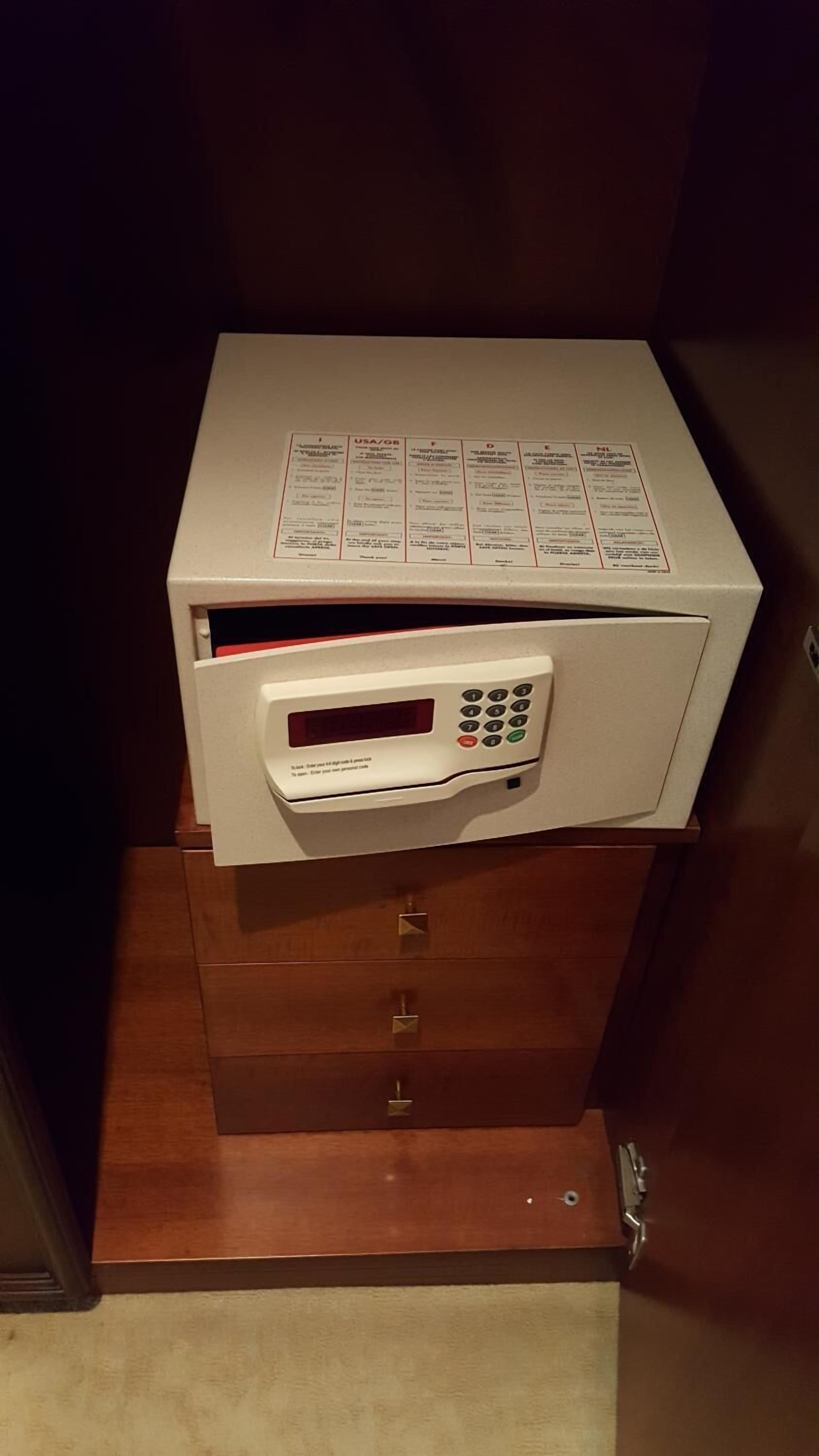 A microwave with a digital display and keypad, placed on a wooden cabinet with a drawer below.