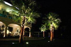 Een nachtzicht van een hotel binnenplaats met palmbomen en terrasmeubels.