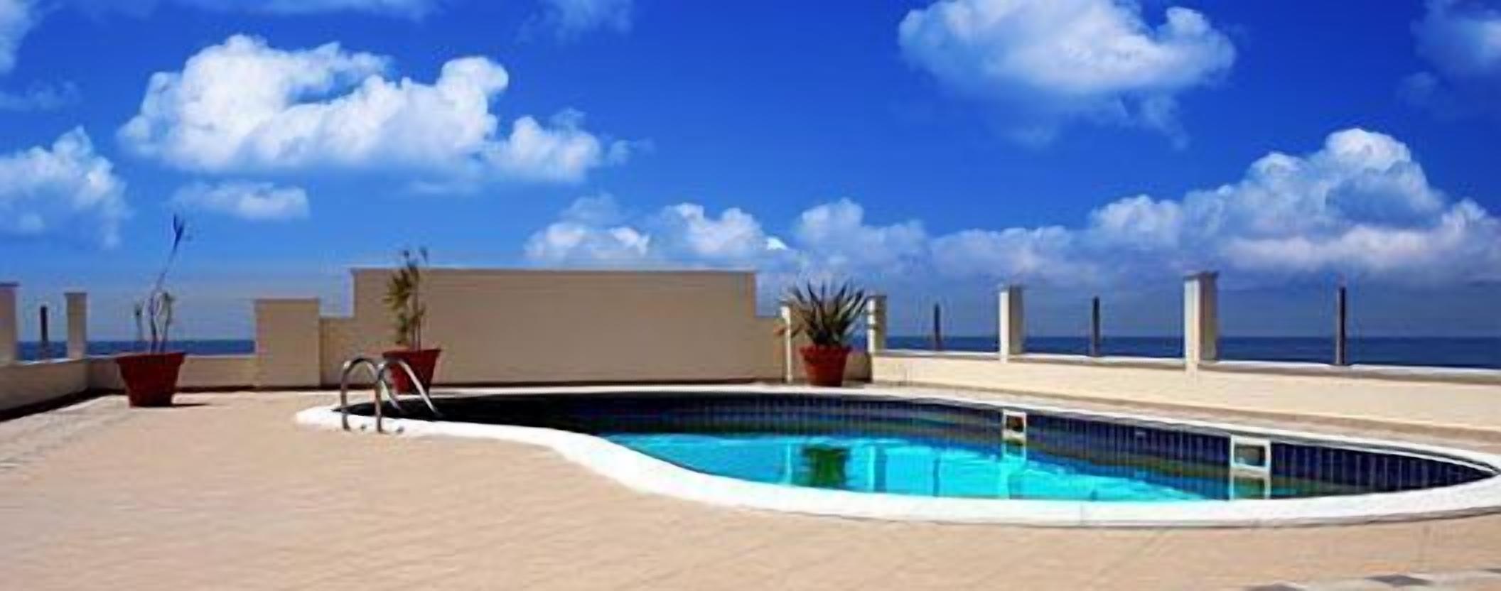 Una piscina con vista libera sull'oceano e una spiaggia sullo sfondo.