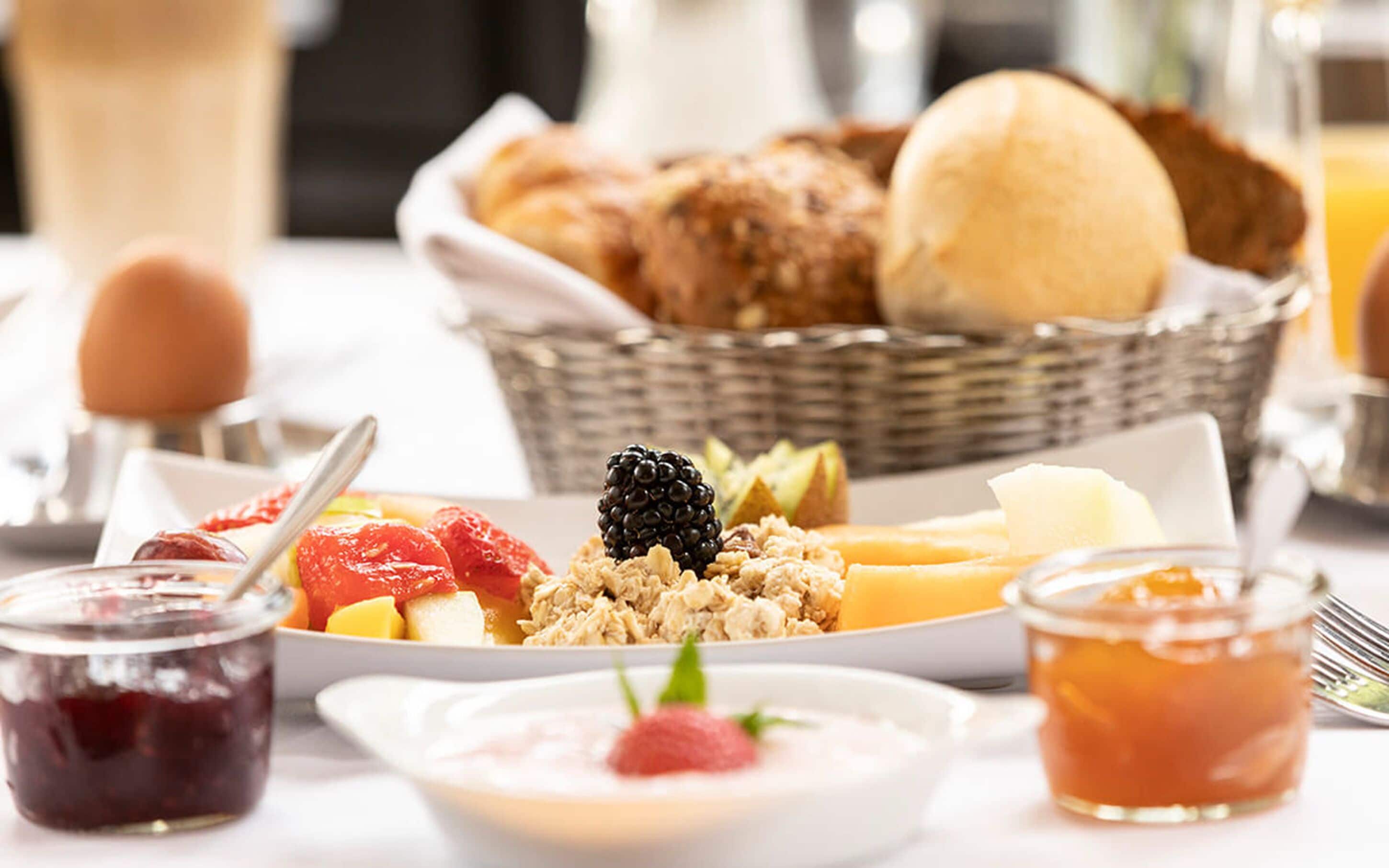 A breakfast buffet with various fruits, pastries, and beverages.