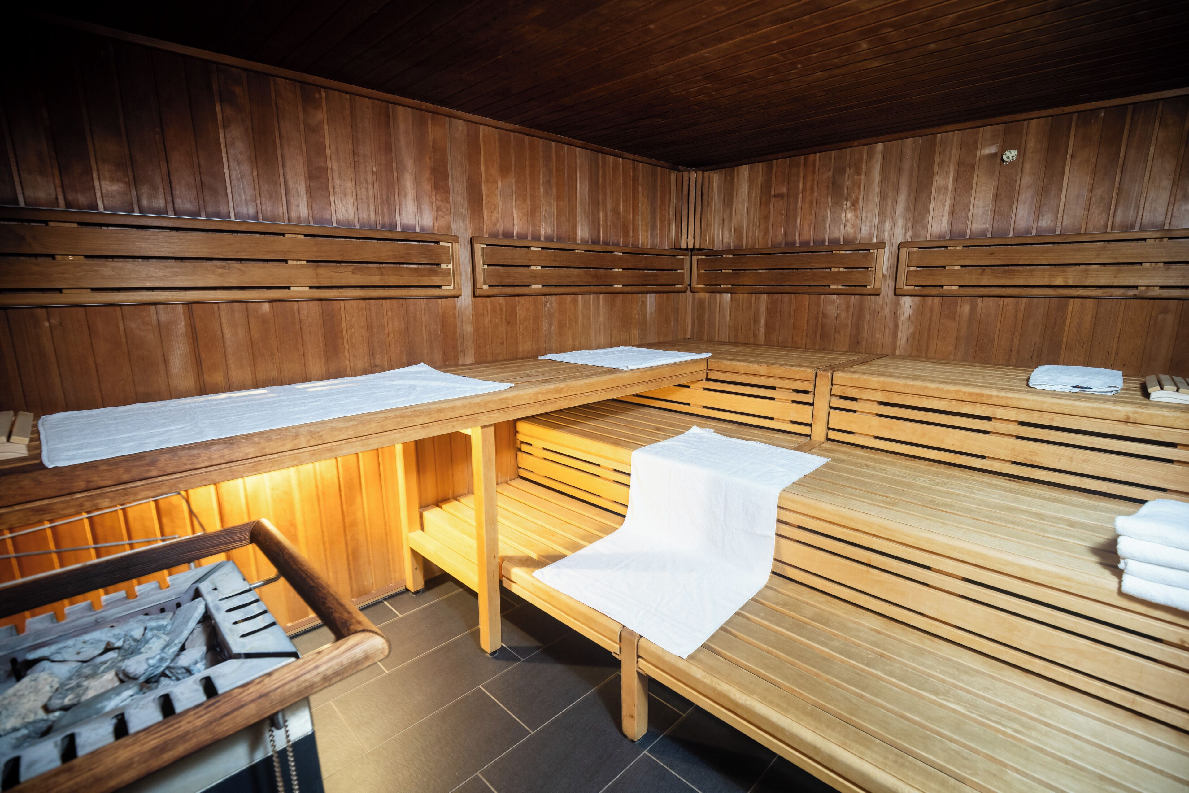 Una sala de sauna con bancos de madera, paredes de madera y un banco con toallas.
